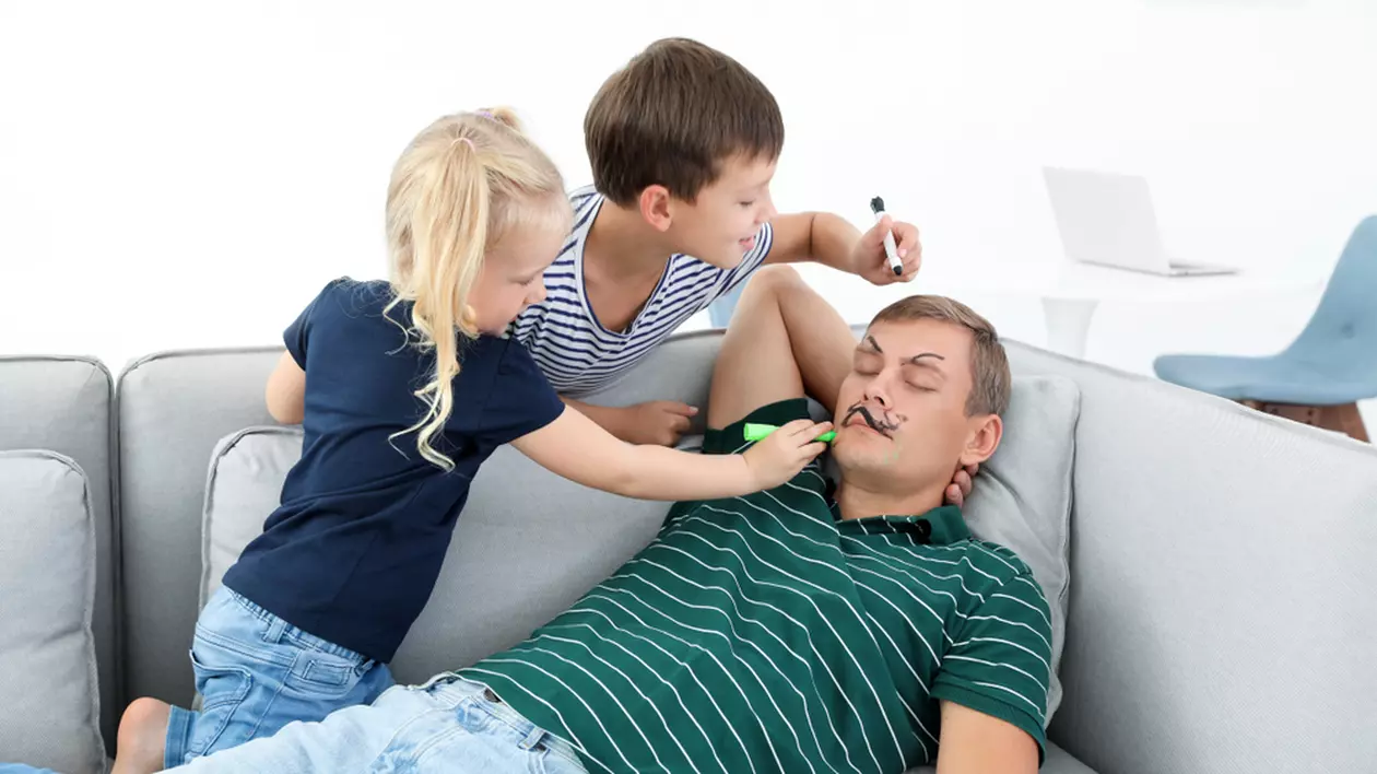 Curiozități despre Ziua Păcălelilor - 1 aprilie - Imagine cu doi copii, băiat şi fată, care îi fac o farsă tatălui lor, pictându-l pe faţă în timp ce doarme, de 1 aprilie