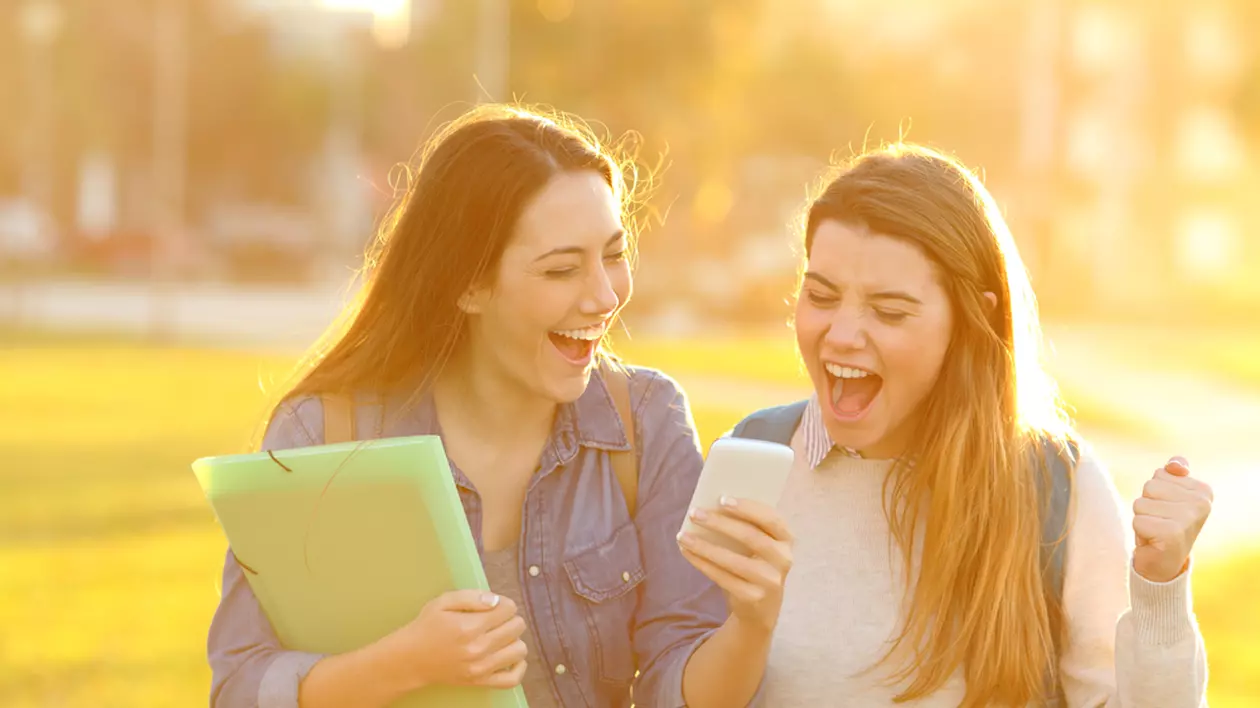Rezultate Evaluare Națională Covasna 2023 - Imagine cu două fete care îşi verifică pe un telefon mobil rezultatele obţinute la examene