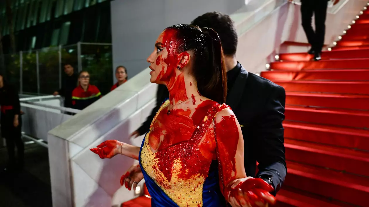 Protest pe covorul roșu de la Cannes. O femeie îmbrăcată în culorile steagului ucrainean s-a stropit cu vopsea roșie