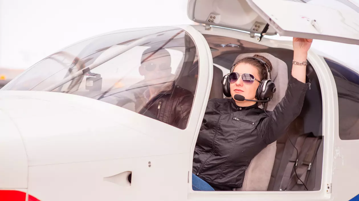 Cum poți lua brevetul de pilot de avion – Imagine cu o tânără aspirantă la brevetul de pilot, aflată într-un avion de mici dimensiuni, alături de instructorul ei