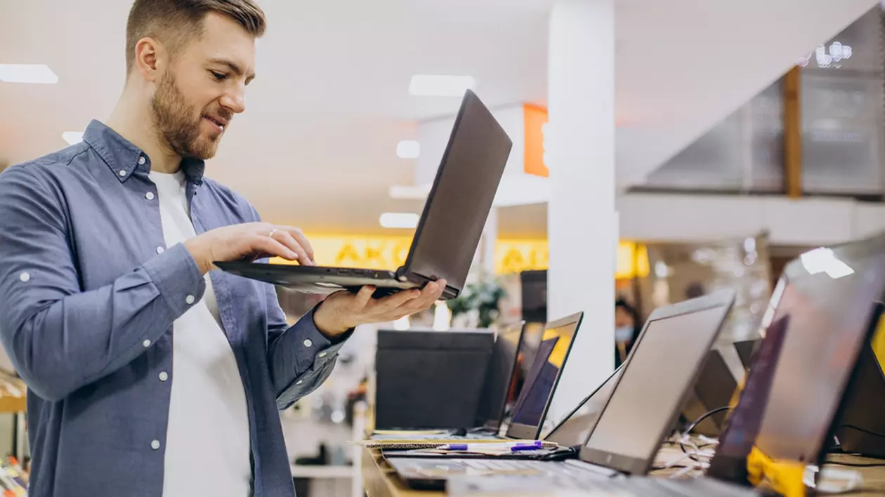 Laptopuri ieftine la eMAG de Black Friday 2023 - Imagine cu un bărbat care testează un laptop într-un magazin IT