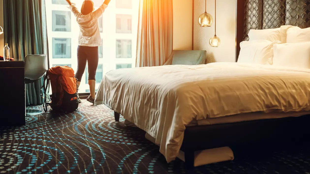 Care sunt cele mai murdare locuri dintr-o cameră de hotel - Imagine cu o turistă care îşi exprimă bucuria odată ajunsă în camera de hotel.