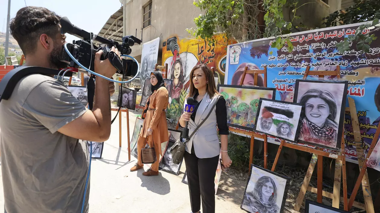 Un reporter Al-Jazeera relatează, pe 19 mai 2022, despre o expoziție de artă în onoarea regretatei sale colege, jurnalista palestiniană Shireen Abu Akleh, în locul în care veterana jurnalistă de televiziune a fost ucisă pe 11 mai în timp ce relata despre un raid al armatei israeliene în Jenin, în Cisiordania ocupată. Foto Profimedia