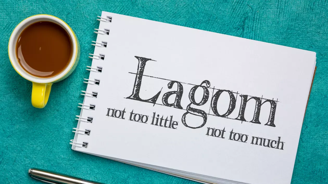 Ce presupune Lagom, stilul de viaţă suedez - Imagine cu un blocknotes pe care scrie Lagom, not too little, not to much", alături de o ceaşcă de cafea, totul pe o masă