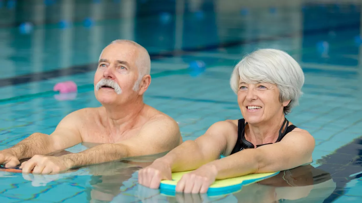 Exerciţii fizice potrivite pentru persoanele în vârstă- Un barbat si o femeie in varsta fac aerobic intr-o piscina acoperita