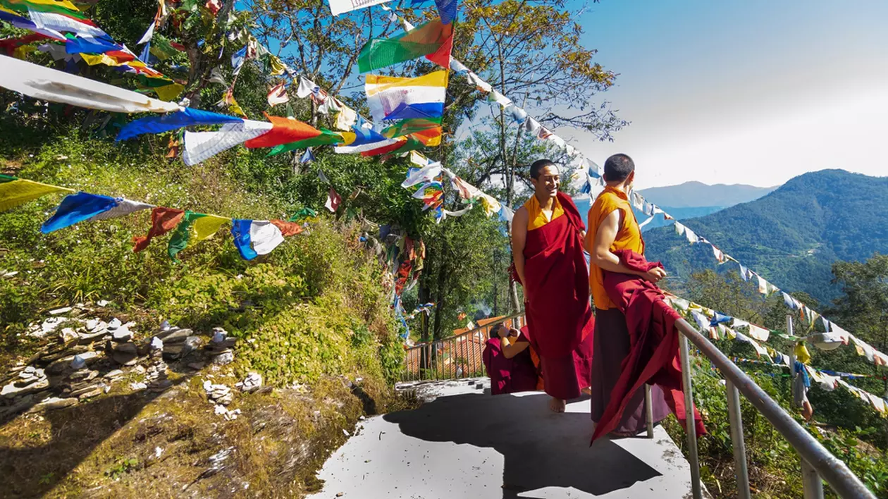 Curiozitati despre Tibet- Priveliștea Munților Himalaya încadrați de șiruri de steaguri colorate, fluturând în bătaia vântului, in timp ce cativa calugari urca scarile pe munte