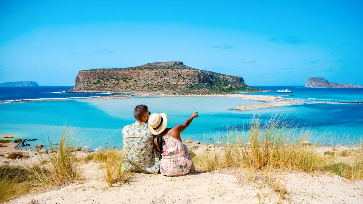 Unde să mergi la mare în octombrie, în Europa - Imagine cu doi turişti care admiră de la înălţime plaja Balos din Creta