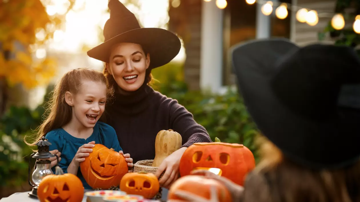 Când este Halloween 2024 – curiozități și tradiții - Imagine cu o mamă tânără care pregăteşte decoraţiuni pentru Halloween cu cele două fiice ale ei.