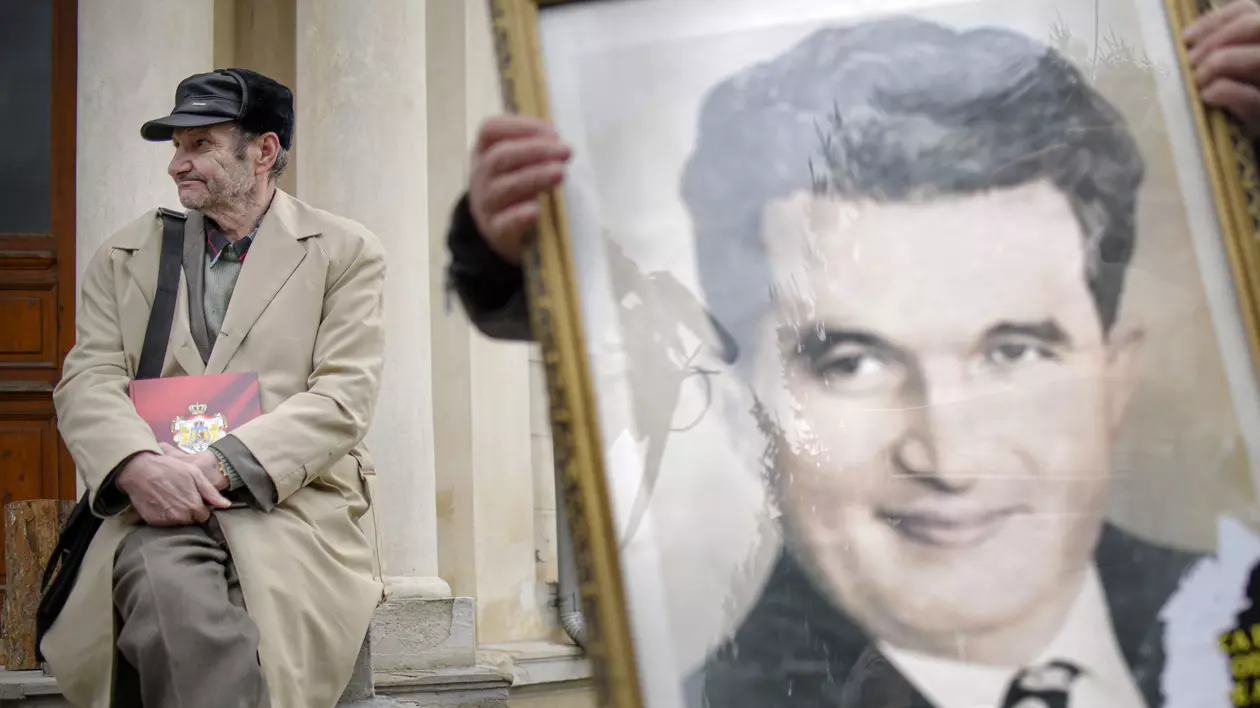 Un barbat sta langa un portret cu Nicolae Ceausescu, in timpul comemorarii a 30 de ani de la moartea cuplului Elena si Nicolae Ceausescu, in cimitirul Ghencea Civil din Bucuresti, miercuri, 25 decembrie 2019. Cuplul dictatorial Elena si Nicolae Ceausescu a fost executat in 25 decembrie 1989, la o cazarma din Targoviste, in urma unui proces, in care cei doi au fost acuzati de genocid. Sentinta data a fost condamnarea la moarte. ANDREEA ALEXANDRU / MEDIAFAX FOTO