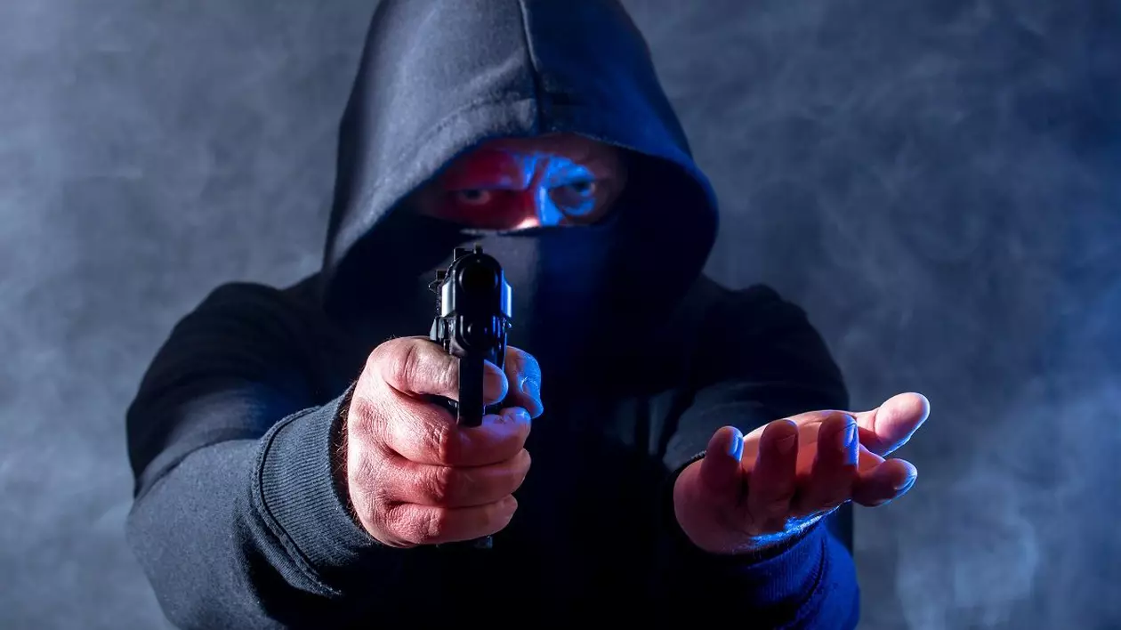 Bărbat cu un pistol în mână îndreptat spre obiectivul camerei de fotografiat