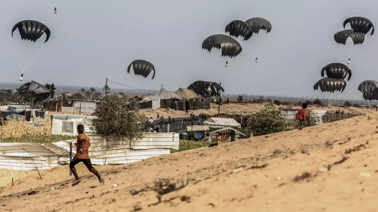 17 October 2024, Palestinian Territories, Al-Mawasi: Displaced Palestinians race to receive food aid, as Emirati humanitarian aid packages land from planes by parachute in Al-Mawasi area, west of Khan Yunis city in the southern Gaza Strip. Photo: Abed Rahim Khatib/dpa