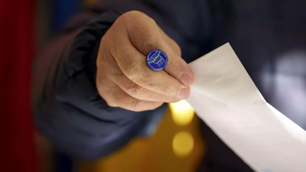 Imagine ilustrativă cu o mână de bărbat care ține o ștampilă de vot și un buletin de vot