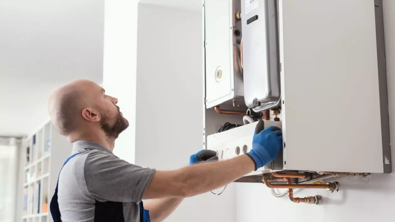 Un instalator fixează o centrală de apartament pe peretele unei camere