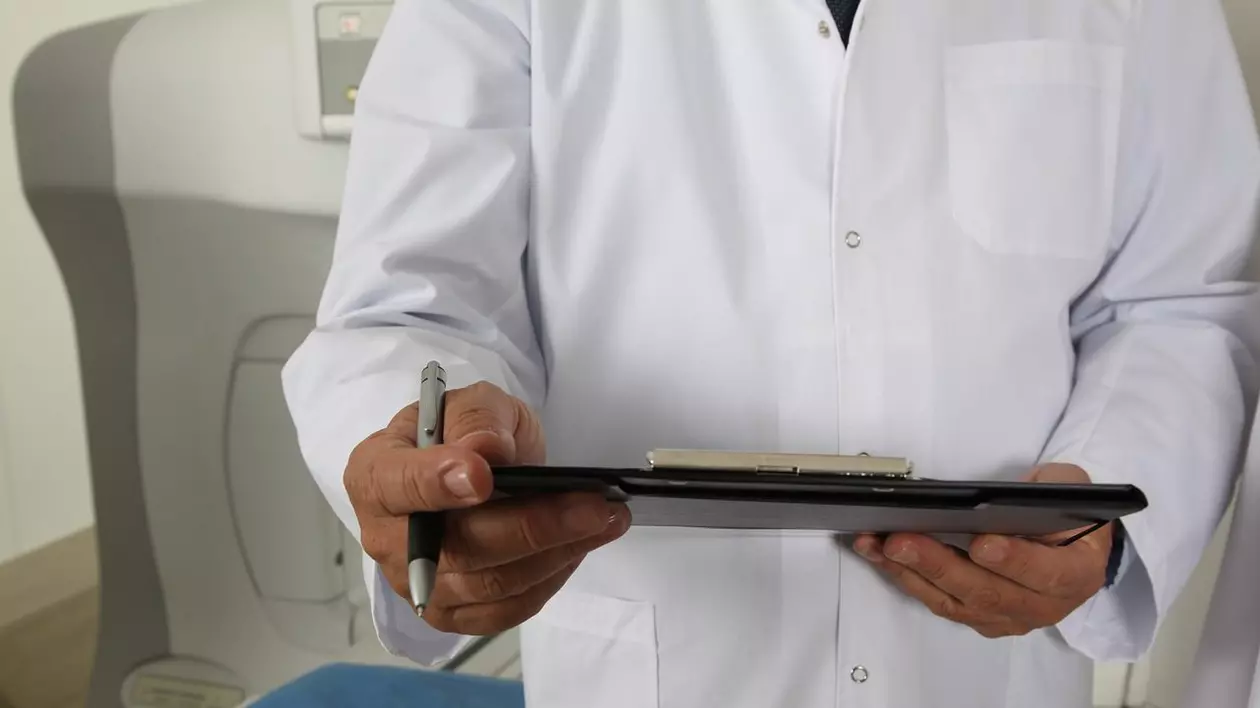 doctor cu documente în mână în fața unui aparat tomograf
