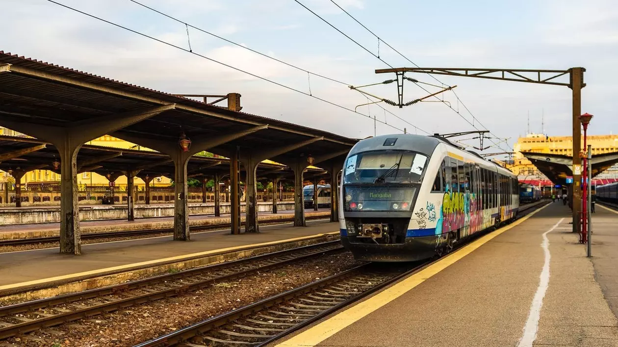 Un tren stă în stație într-o gară, iar peronul este gol