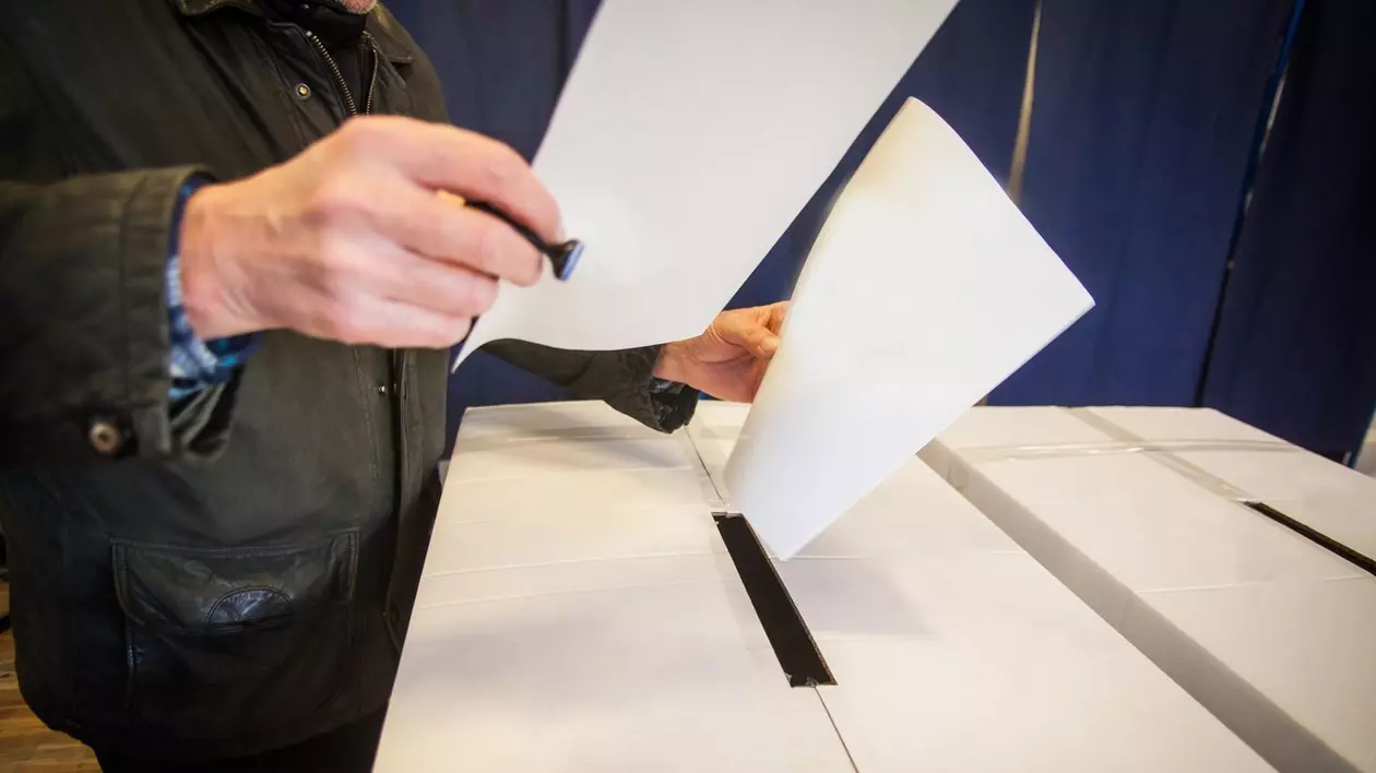 barbat care introduce două buletine de vot în urnă