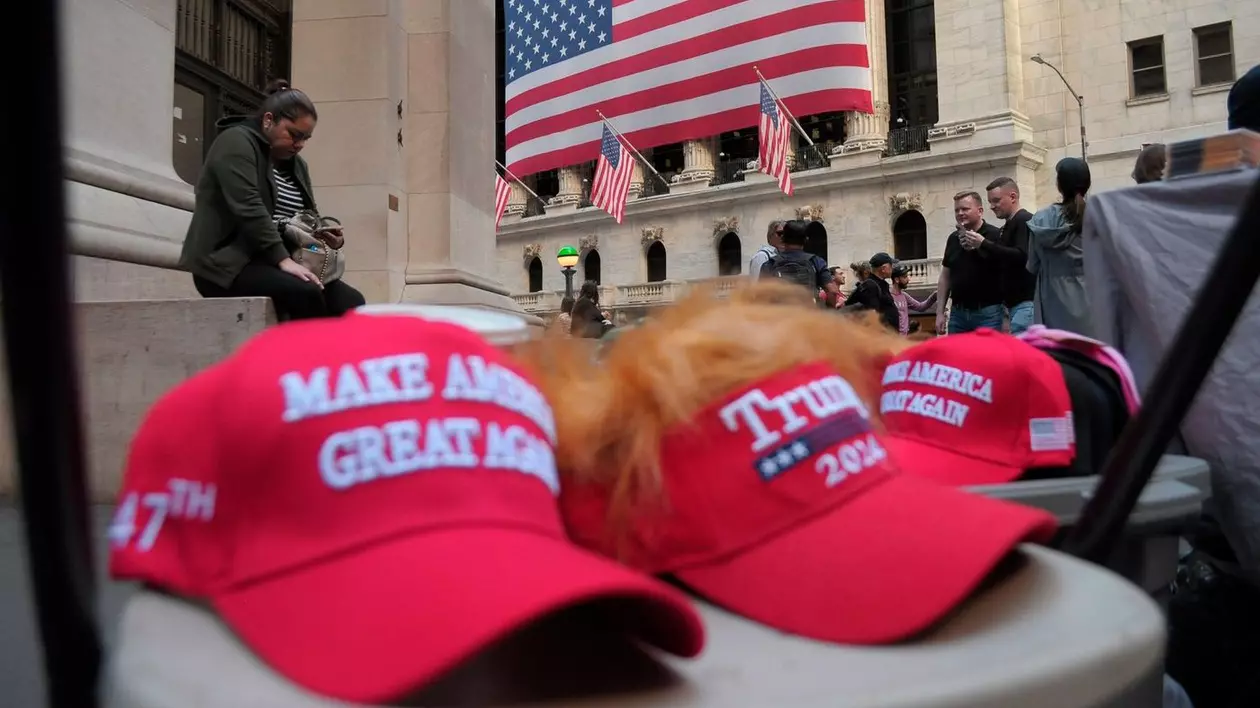 Șepci cu sloganul lui Donald Trump: „Make America Great Again”, vândute la New York, în spate se vede steagul SUA