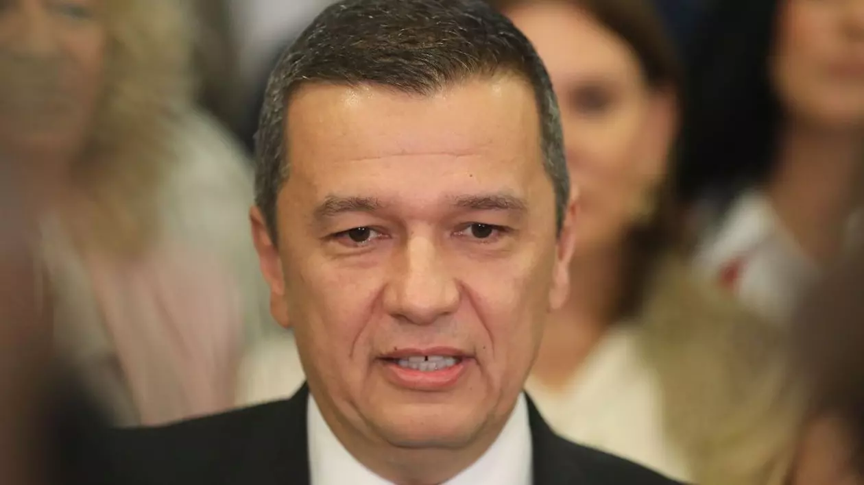 Sorin Grindeanu, ministrul Transporturilor, în prim plan, cu câțiva oameni în spate care apar blurați