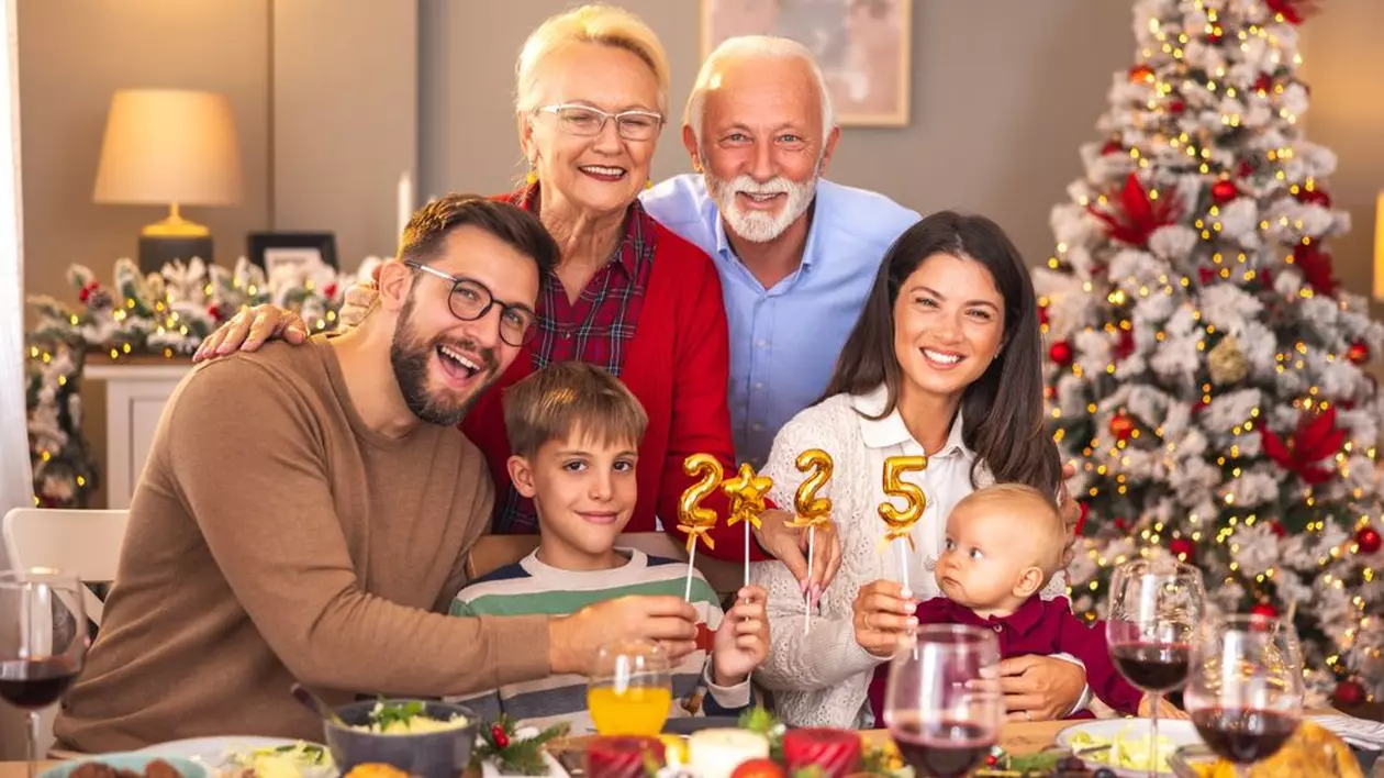 O familie cu doi copii sta la masa de Revelion, iar bunicii stau la poza in spatele lor
