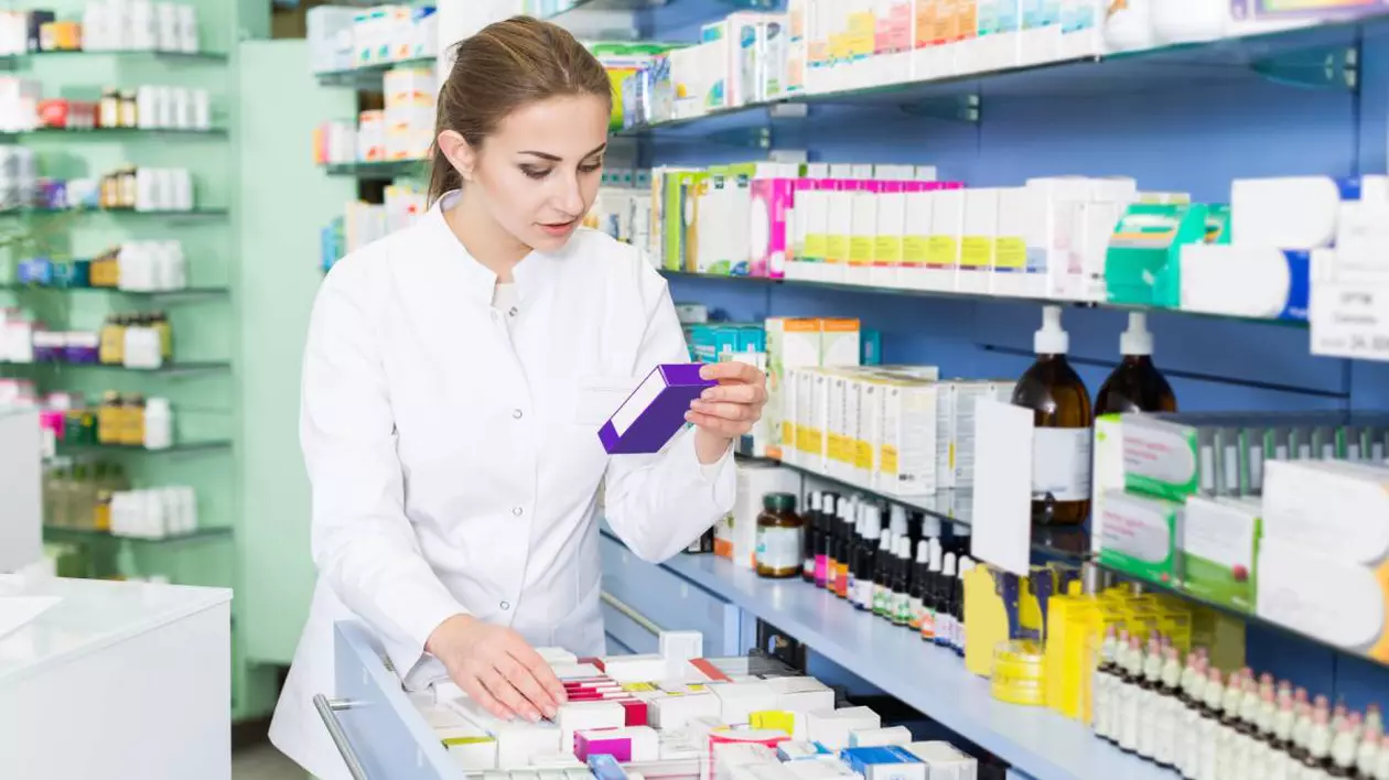 farmacista citind prospectul unui medicament intr-o farmacie