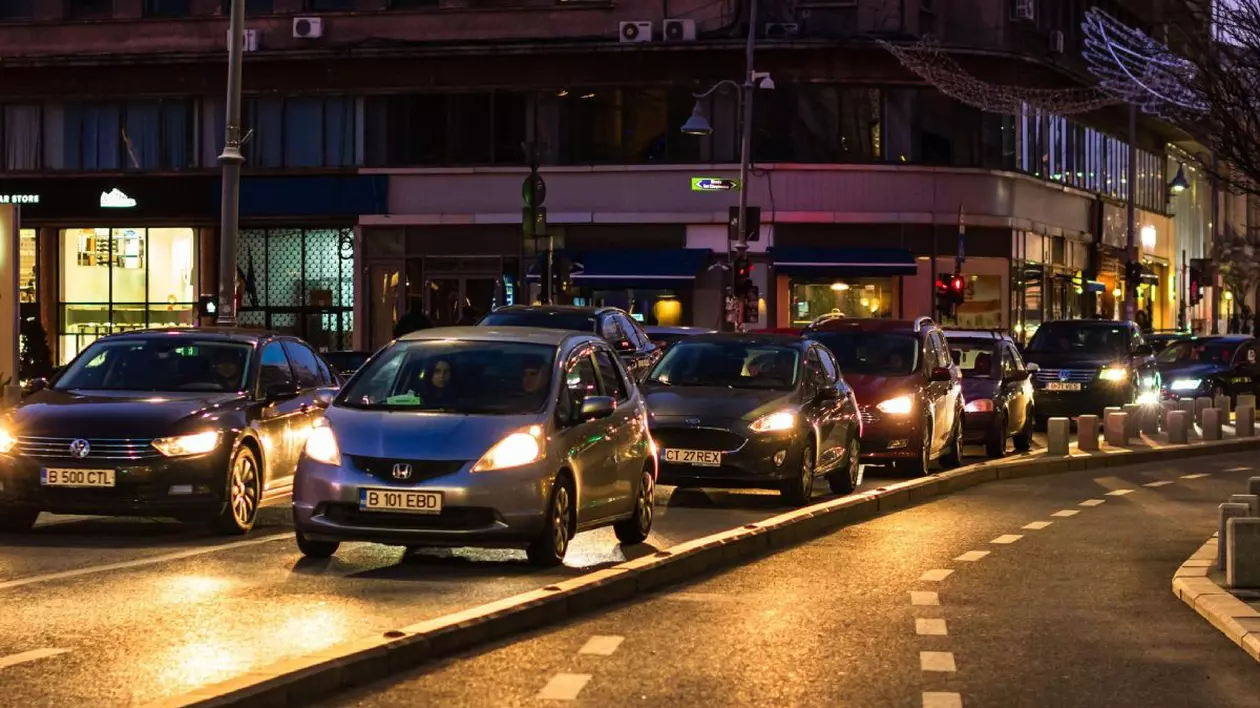 Mașini în traficul din București, noaptea, cu farurile aprinse, în timp ce așteaptă la semafor