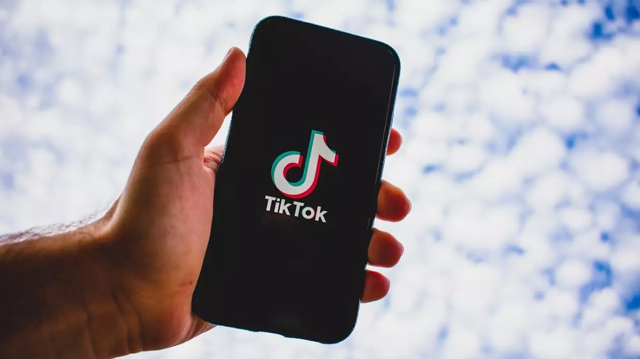 Un bărbat ține în mână un telefon , pe ecranul căruia este TikTok și apare sigla acesteia. Foto: pixabay.com