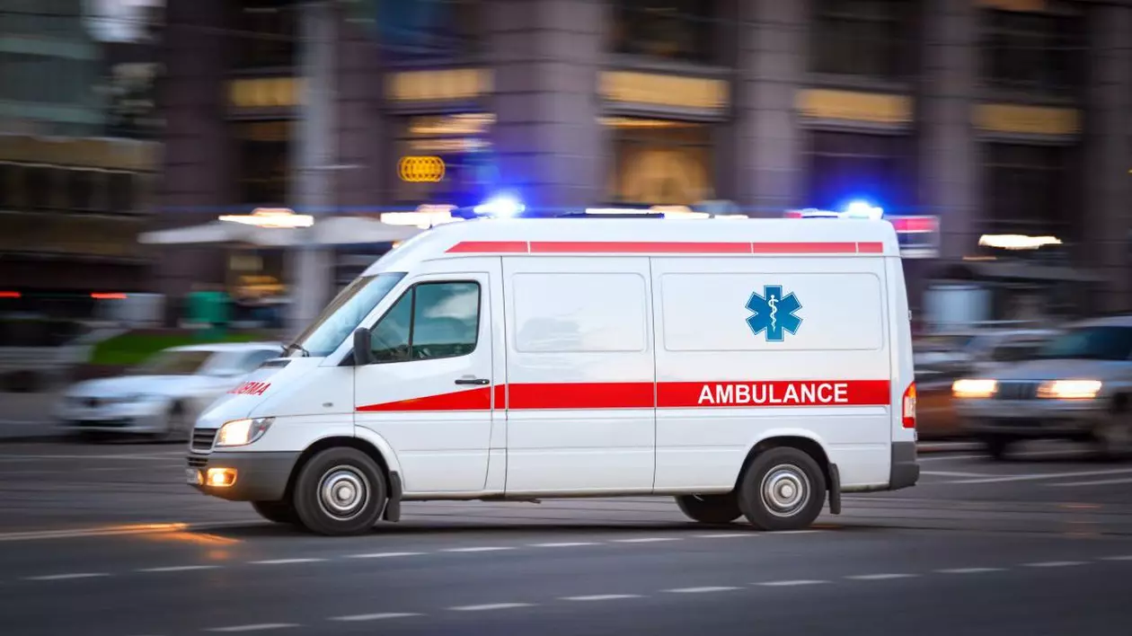 O mașină a Ambulanței în trafic, cu luminile aprinse, într-un fundal neclar.