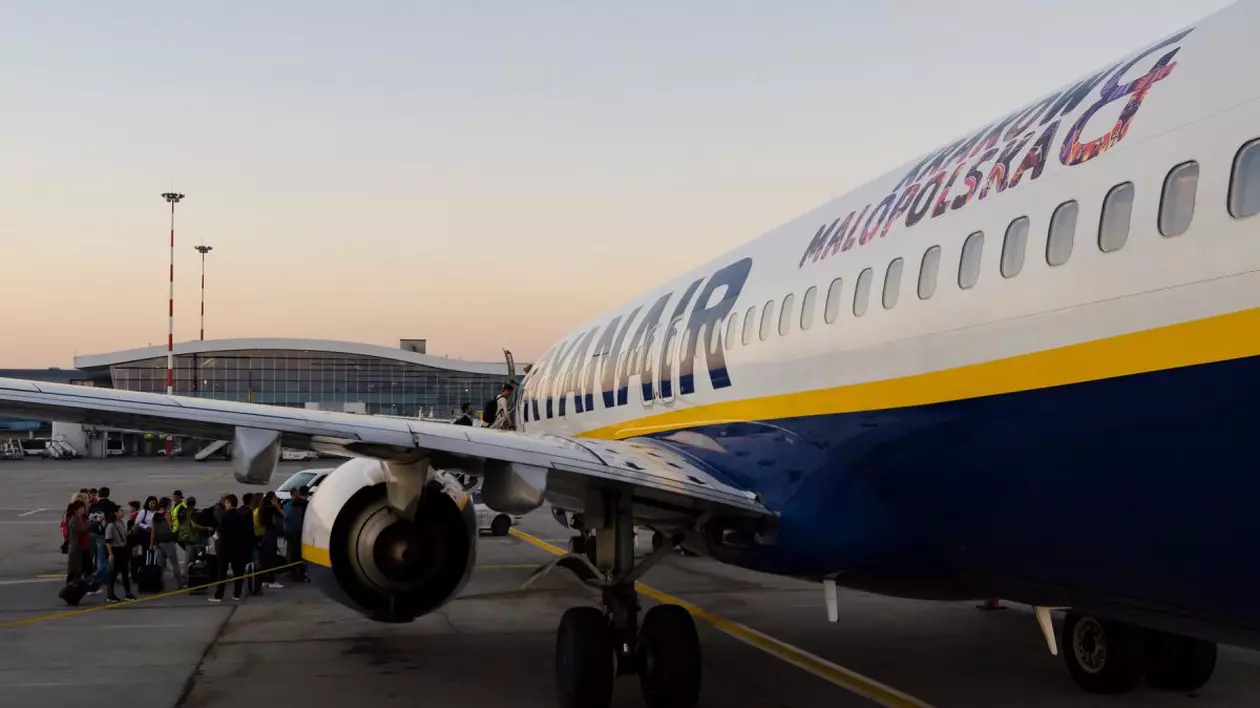 Pasageri care se îmbarcă într-un avion Ryanair, pe pista aeroportului Otopeni din București, când răsare soarele