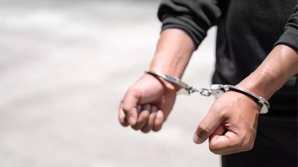 bărbat îmbrăcat într-o cămașă neagră, cu cătușe metalice pe mâini