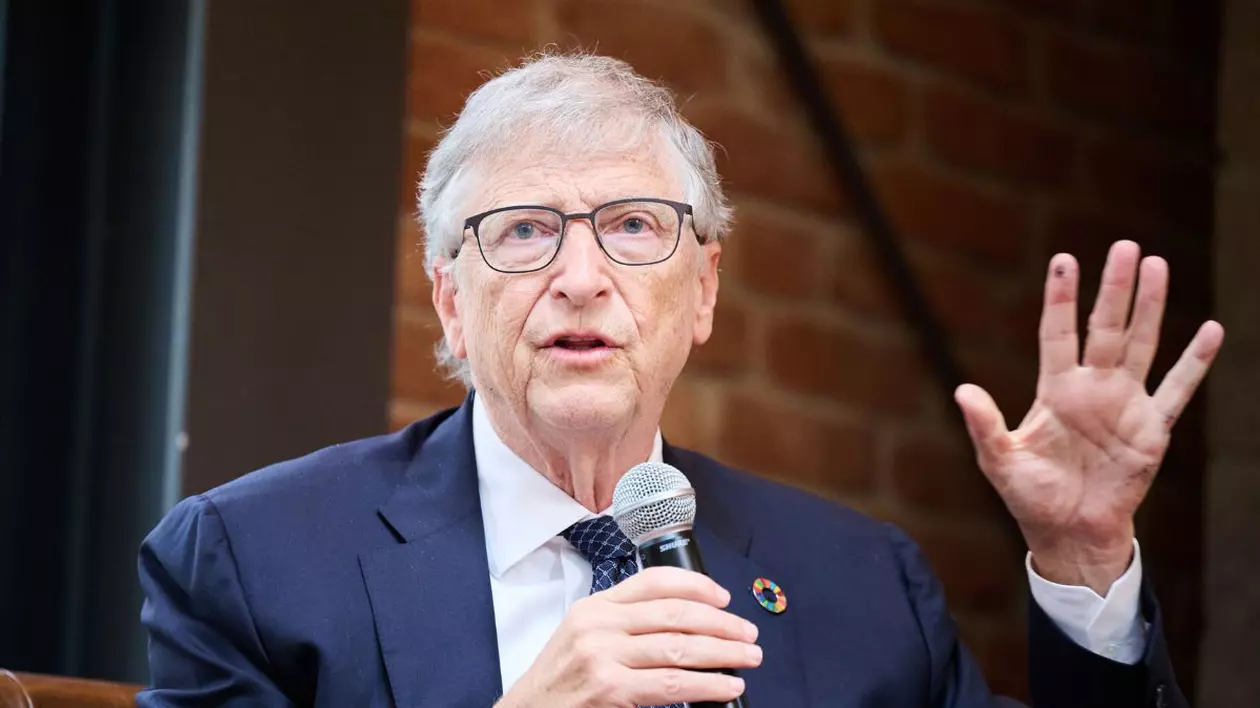 Bill Gates în timpul unui interviu, purtând un costum albastru închis și o cravată neagră, cu un microfon în mână