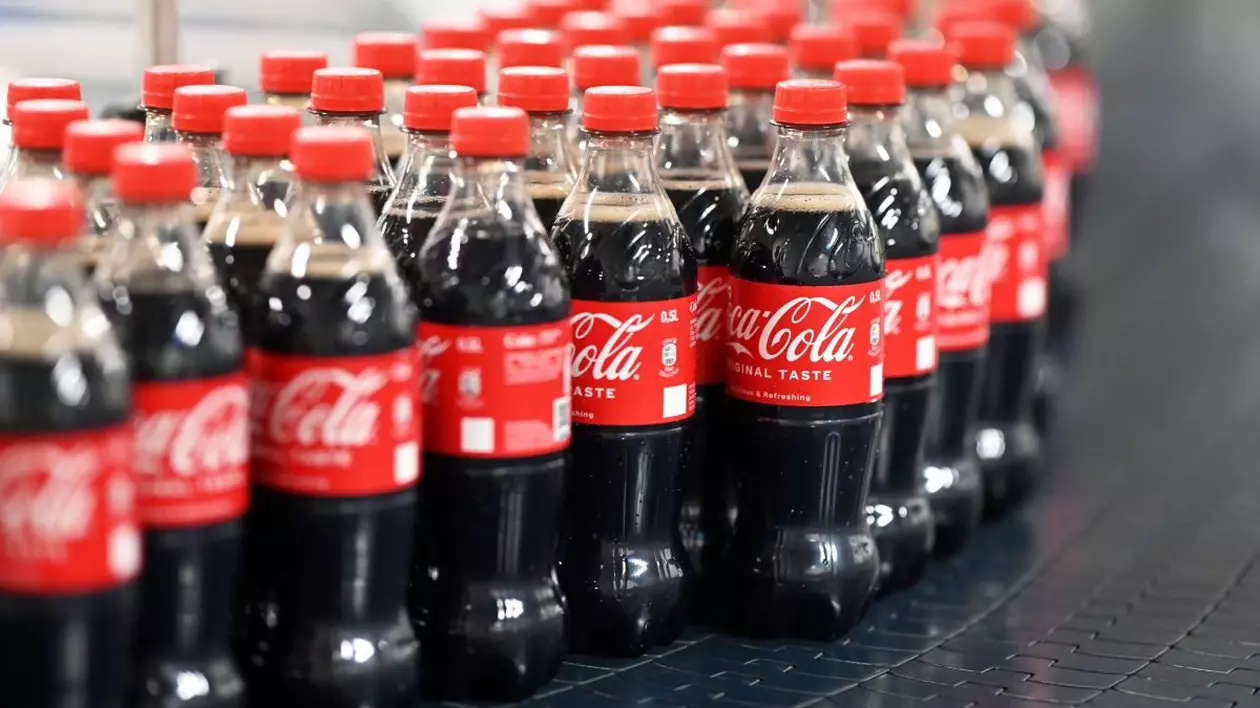 Mai multe sticle de Coca-Cola pline cu suc sunt transportate pe bandă
