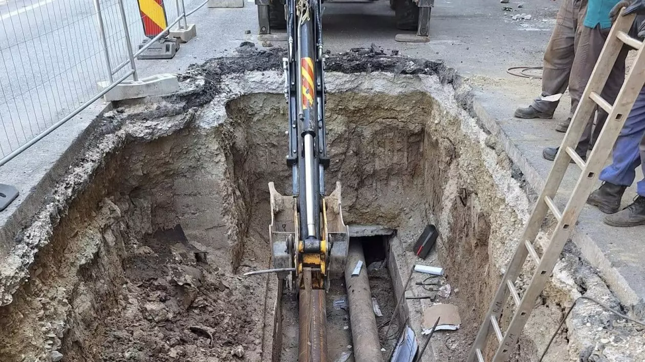 Mai mulți muncitori lucrează la schimbarea unor țevi, după ce a apărut o avarie la conductele de apă caldă