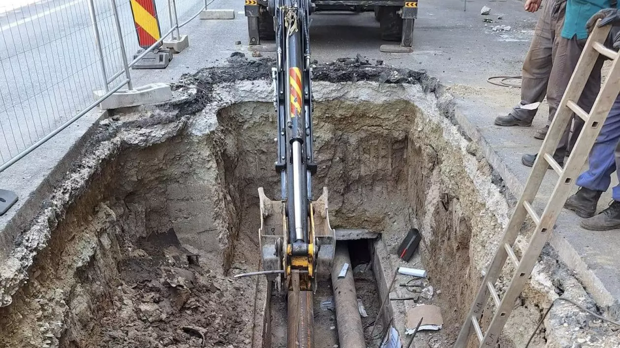 Mai mulți muncitori lucrează la schimbarea unor țevi, după ce a apărut o avarie la conductele de apă caldă