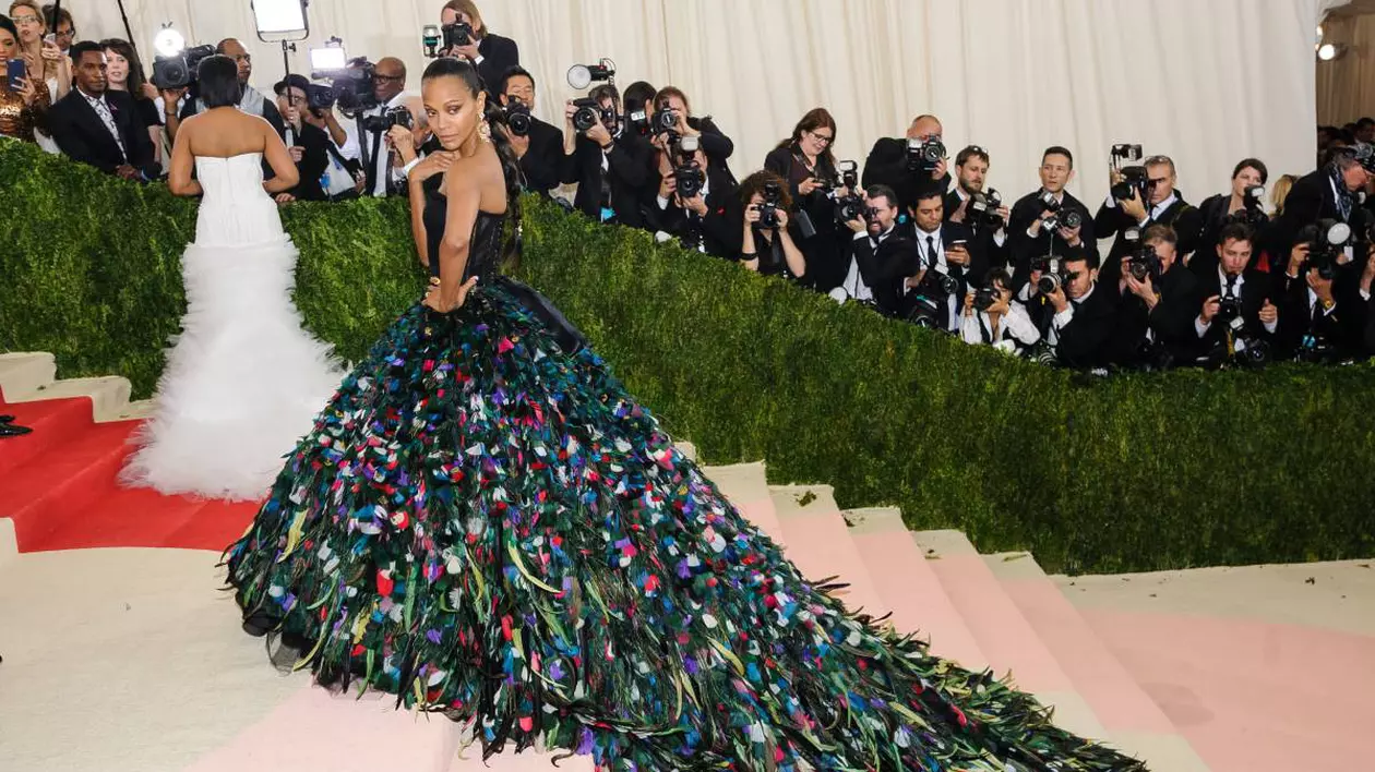 Zoe Saldana la MET Gala cu o rochie plina cu flori colorate, in spate sunt foarte multi fotografi