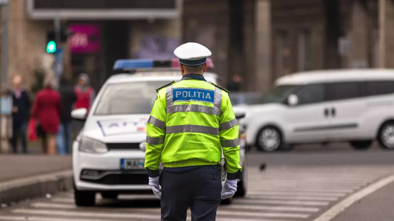 agent politie imbracat in uniforma pe fundal masina de politie