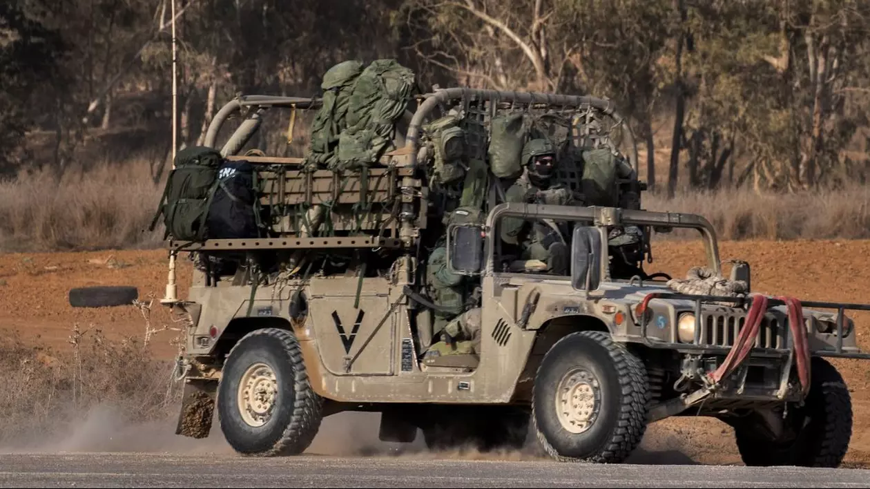 Soldați înarmați într-un Humvee se îndreaptă spre un obiectiv