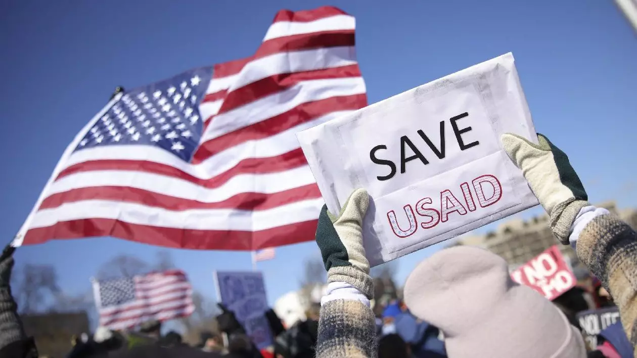 Un manifestant ține o pancartă pe care scrie „Salvați USAID” în timpul unui protest împotriva Proiectului 2025 și a administrației Trump la Capitol Reflecting Pool, lângă Capitoliul SUA din Washington, D.C., pe 17 februarie 2025