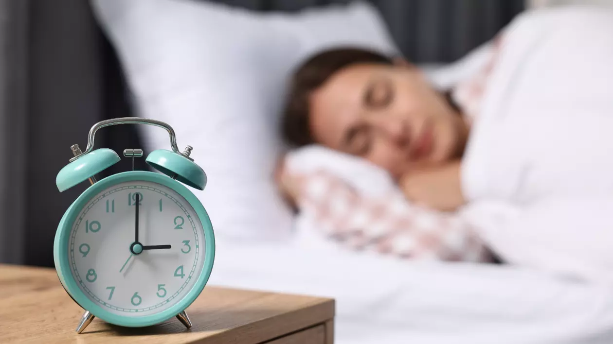 O femeie care doarme și o alarmă pe noptieră