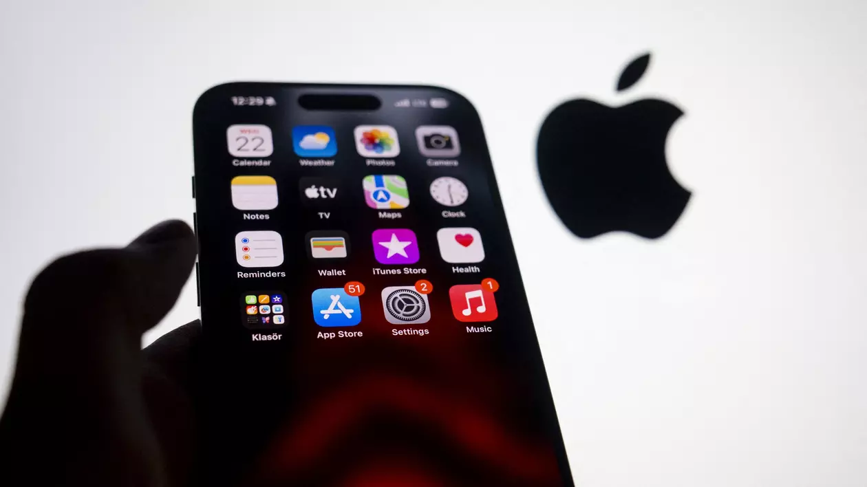 Un telefon Apple iPhone 15 Pro ținut în mână, cu logo-ul Apple pe fundal.