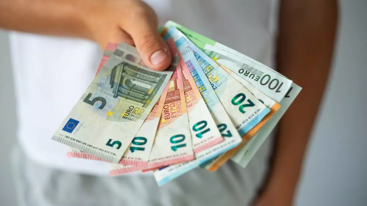 bărbat care ține în mână bancnote de 5, 10, 20, 50 și 100 de euro