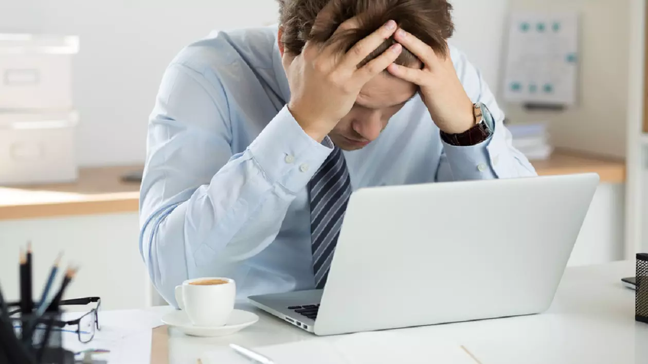 Schimbarea orei. Când se trece la ora de vară 2025 - Imagine cu un bărbat care îşi ţine capul în mâini, în faţa unui laptop
