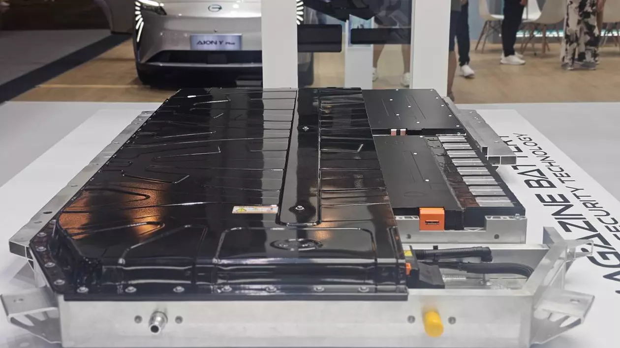 bateria unei masini electrice expusa la o expozitie, pe fundal este o masina electrica gri