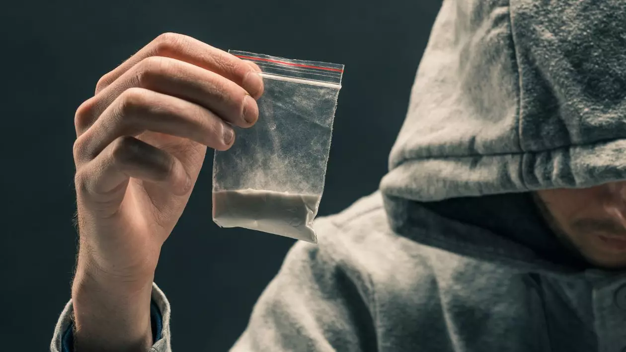 Bărbat care ține în mână o pungă transparentă de plastic cu o pudră albă
