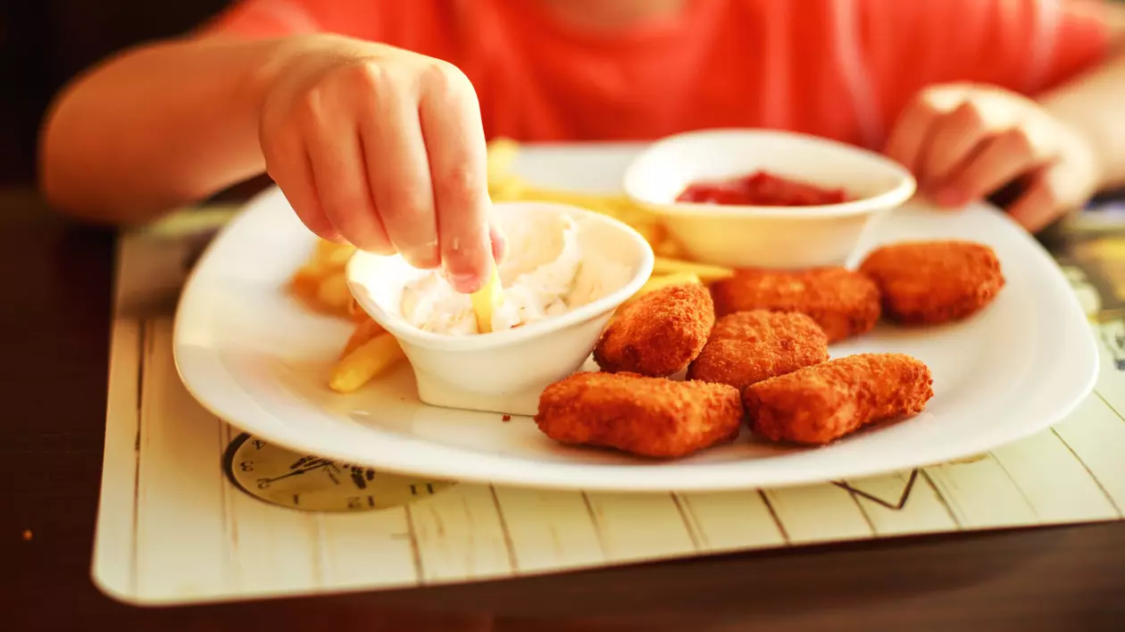 copil aflat la masa care mananca nuggets