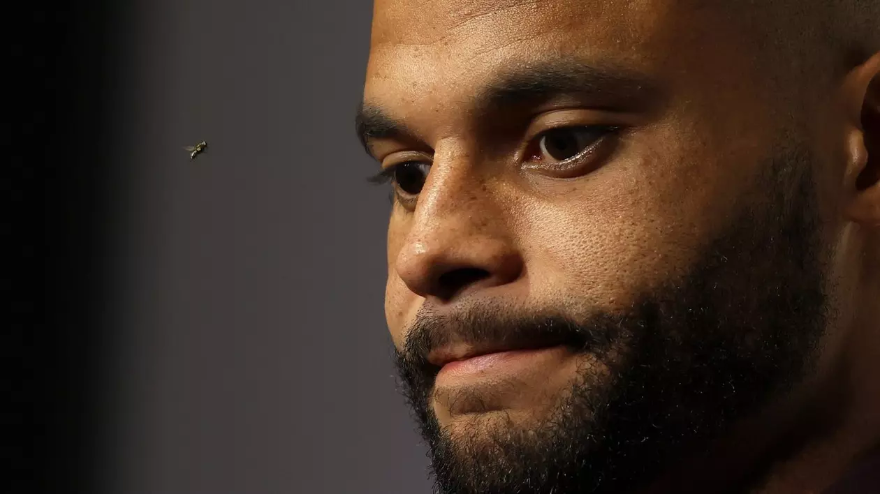 Fundașul echipei Dallas Cowboys, Dak Prescott, răspunde întrebărilor reporterilor în timp ce o muscă trece pe lângă el în timpul unei conferințe de presă după un meci de fotbal american din NFL