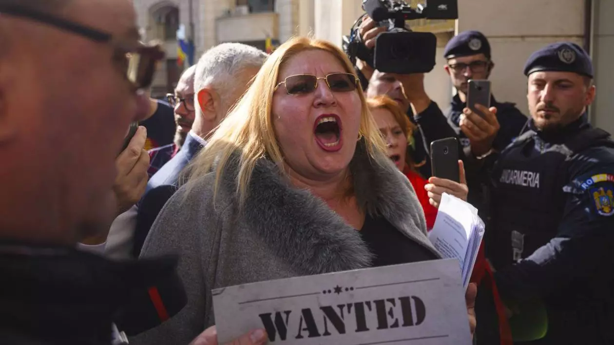 diana sosoaca in timp ce urla inconjurata de oameni si jandarmi cu o foaie in mana pe care scrie wanted