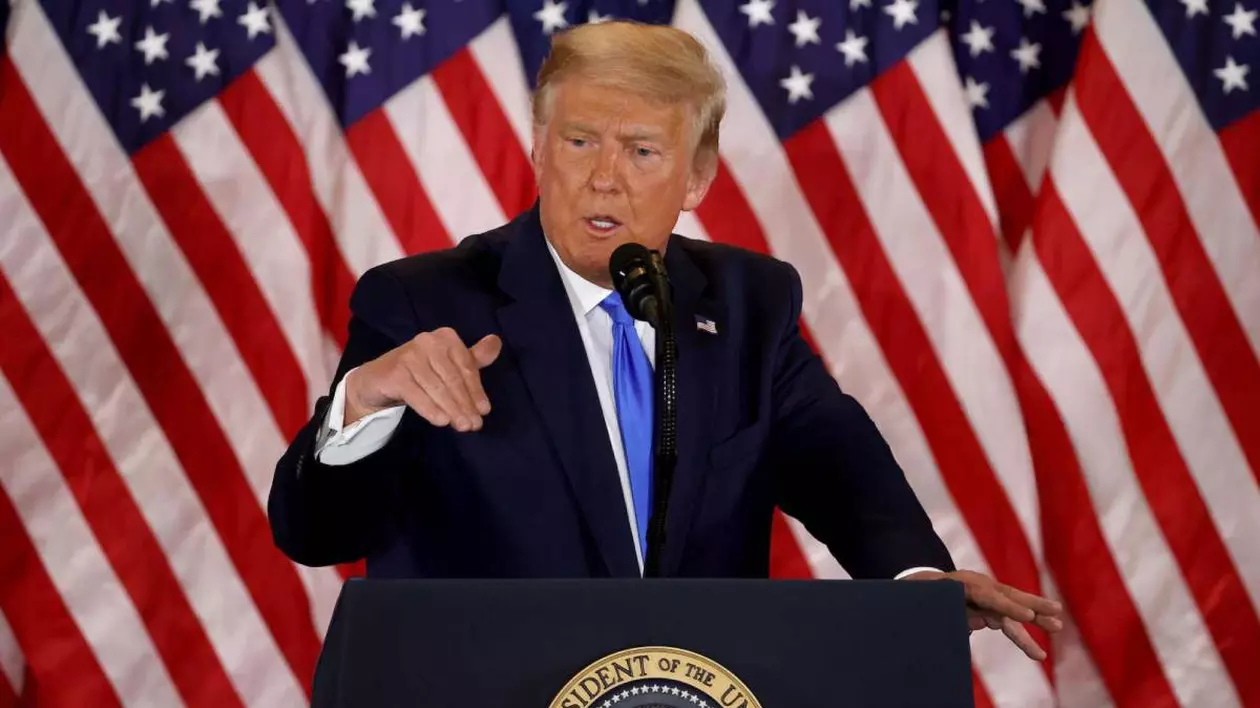 donald trump in timpul unui discurs, in spatele sau steagul americii