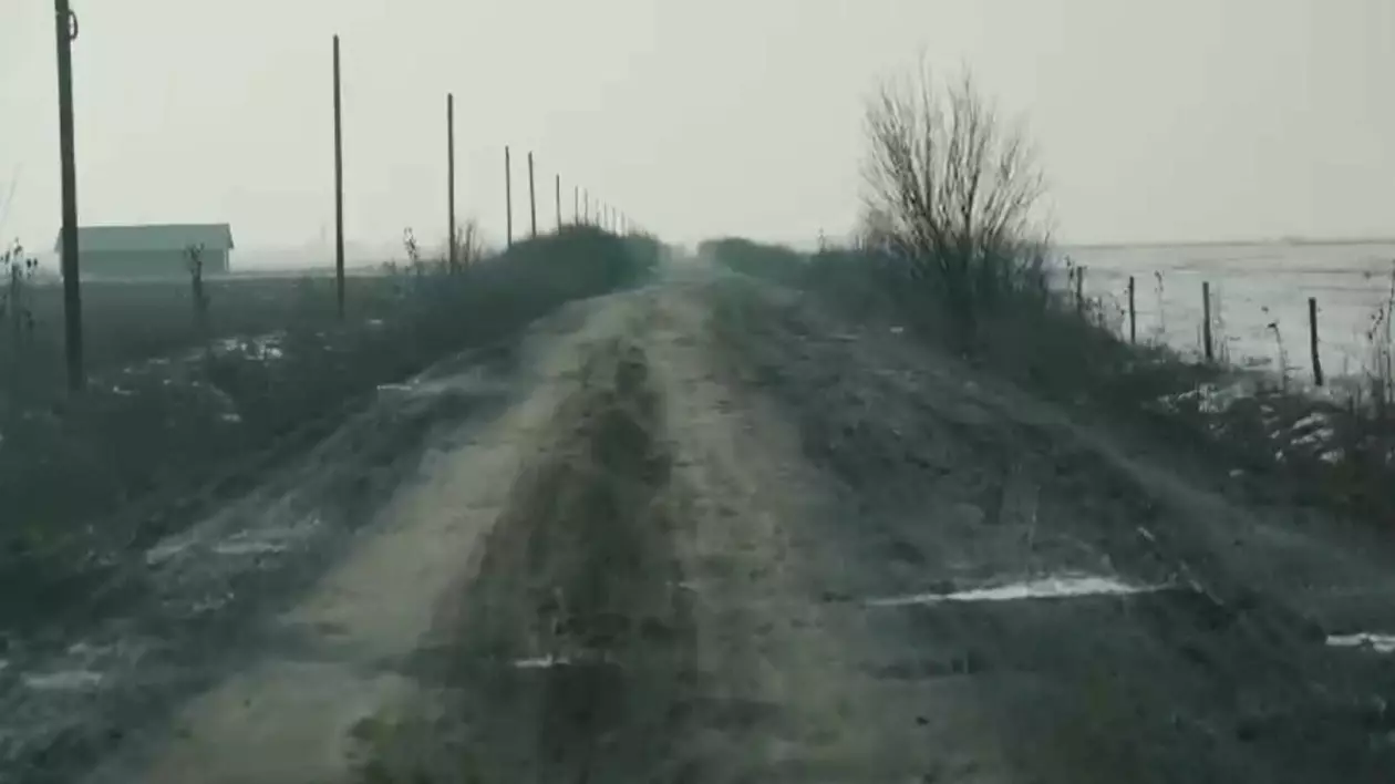 În imagini se vede un drum de pământ, plin de gropi, intr-o zi de iarnă, Drumul oaselor,Sânmiclăuș, Satu Mare, Sursă foto: Captura Video