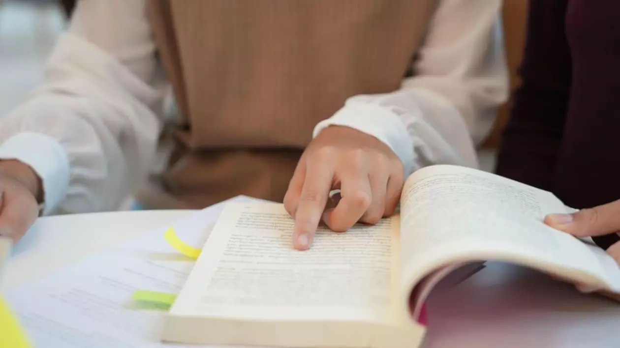 Elev face teme, citeste urmărind scrisul pe carte