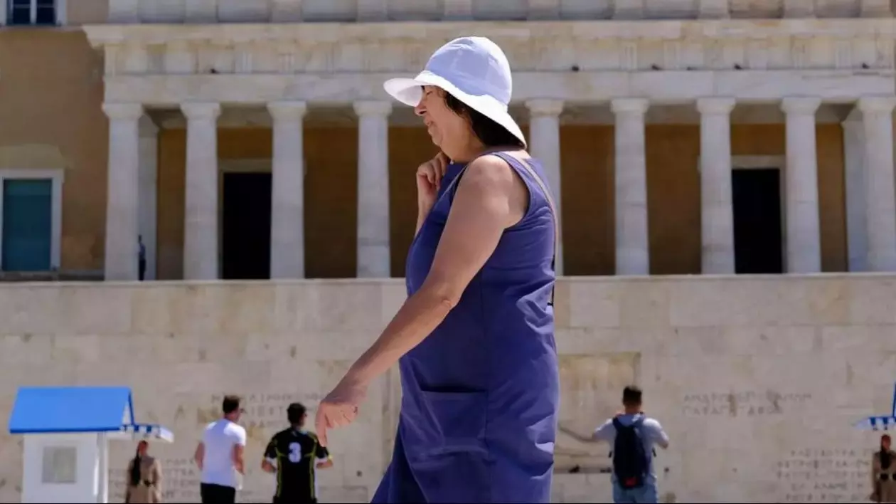 Femeia îmbrăcată în albastru merge cu greutate pe stradă din cauza căldurii